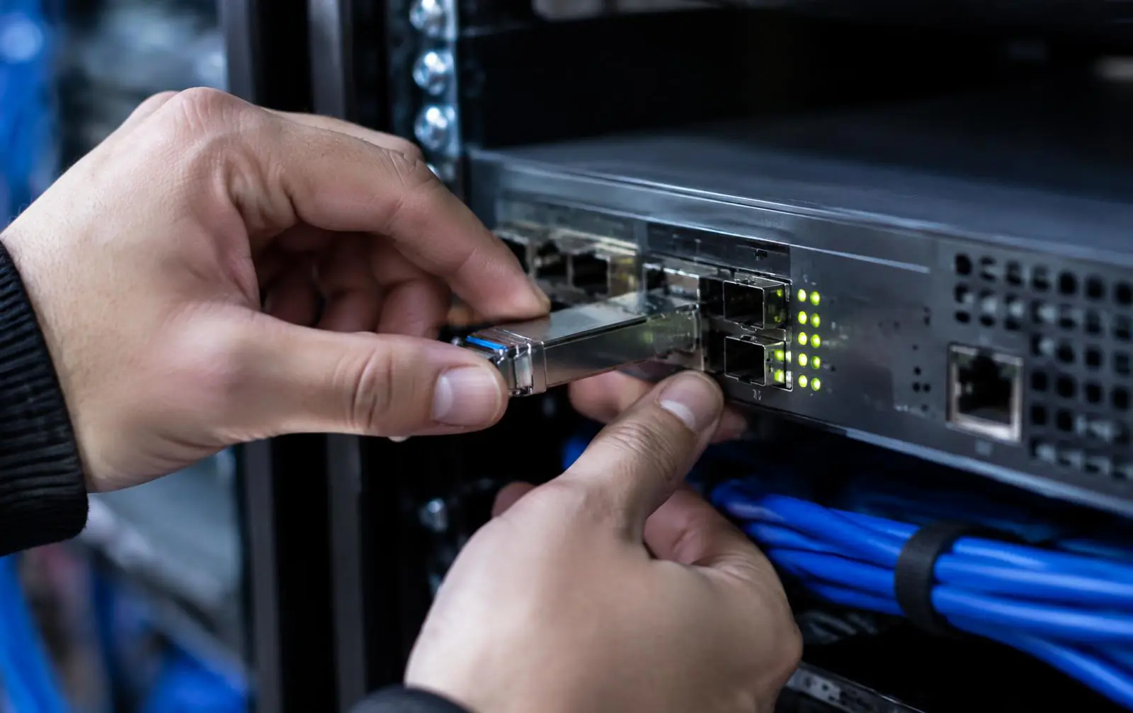 Manos de técnico insertando un transceptor óptico en un router de rack